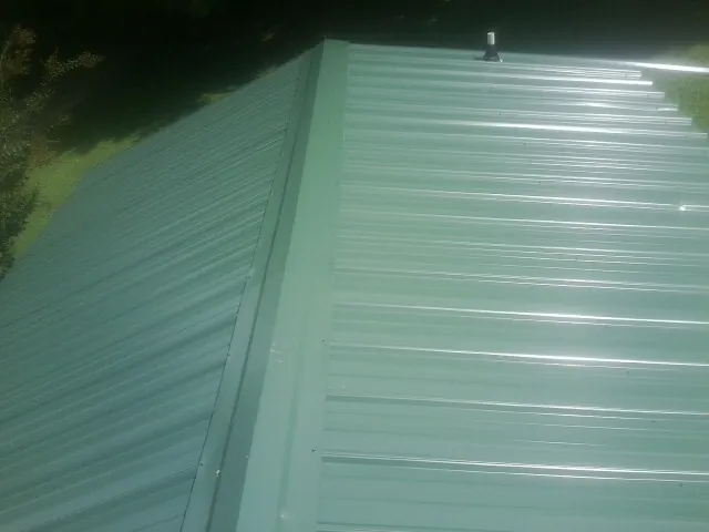 New green metal panels meeting at the ridge of a roof — Flat Roof Repair work by our crew in Fountain